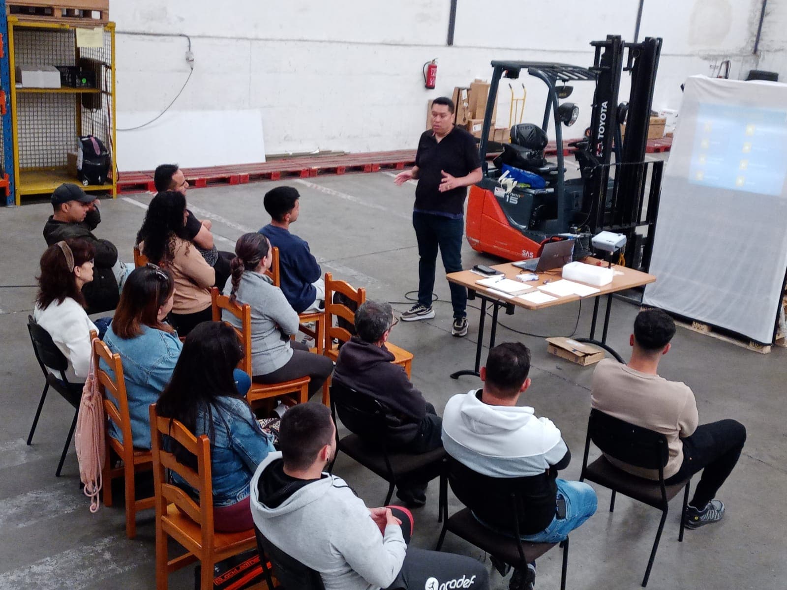 Clase práctica en patio: uso de grúa para carga de palets como ejercicio demostrativo.